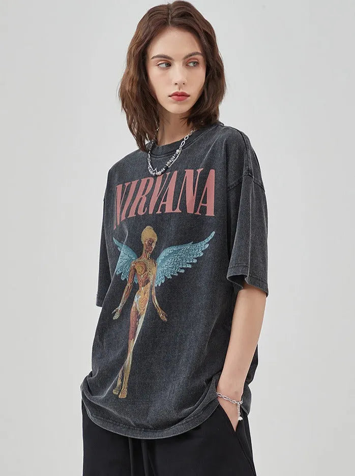 Frau trägt ein schwarzes Nirvana-Bandshirt mit Engelsmotiv, lässiger Stil, ideal für Rock-Mode, Streetwear, Vintage-Look.