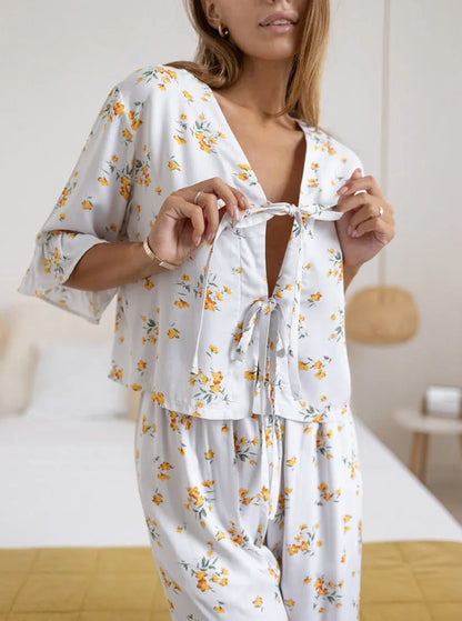 Frau in geblümtem Pyjama-Set, bestehend aus lockerem Oberteil und Hose, ideal für bequeme Nachtwäsche. Perfekt für entspannte Abende zu Hause.