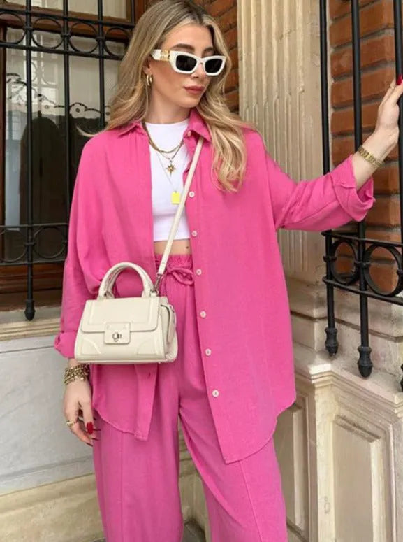 Frau in pinkem Oversize-Hemd und Hose, trägt weiße Sonnenbrille und cremefarbene Handtasche. Modetrend, Streetstyle, Sommermode, Damenbekleidung.