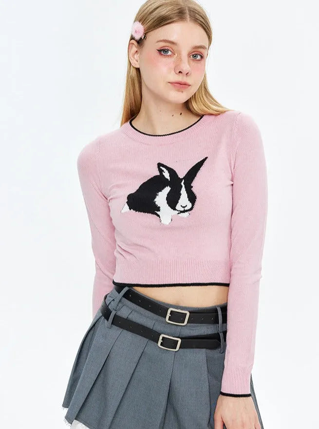 Damen-Pullover in Rosa mit Hasenmotiv, kombiniert mit grauem Faltenrock. Modetrend, Herbstmode, stylische Damenbekleidung.