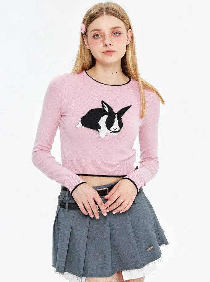 Junge Frau in rosa Pullover mit Kaninchenmotiv, grauem Faltenrock. Modetrend, lässiger Stil, jugendliche Kleidung, Streetwear.