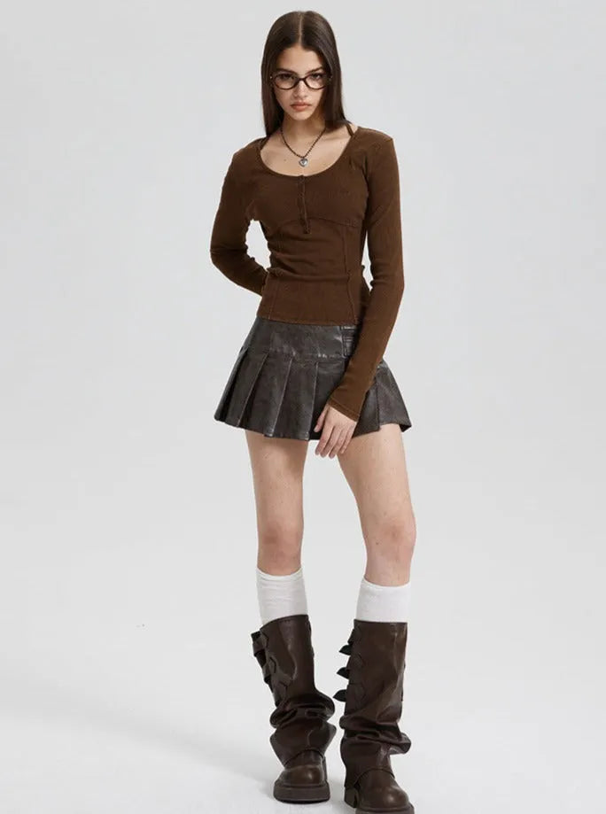 Frau in braunem Langarmshirt, schwarzem Faltenrock und hohen Stiefeln. Modetrend, Herbstmode, Damenbekleidung, stilvoll, modern.