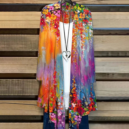 Bunte Damenjacke mit Blumenmuster, lang, offen, über weißem Top, hängend auf Holzkleiderbügel.