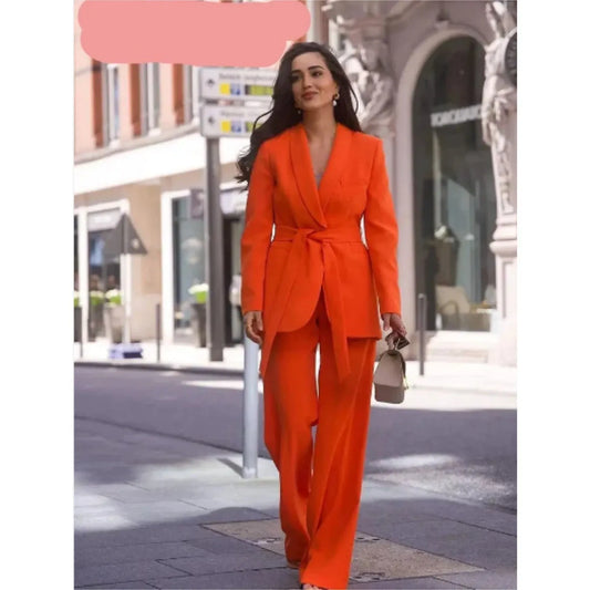 Frau in leuchtend orangefarbenem Anzug spaziert stilvoll durch die Stadt. Modetrend, Damenmode, eleganter Hosenanzug, Streetstyle.