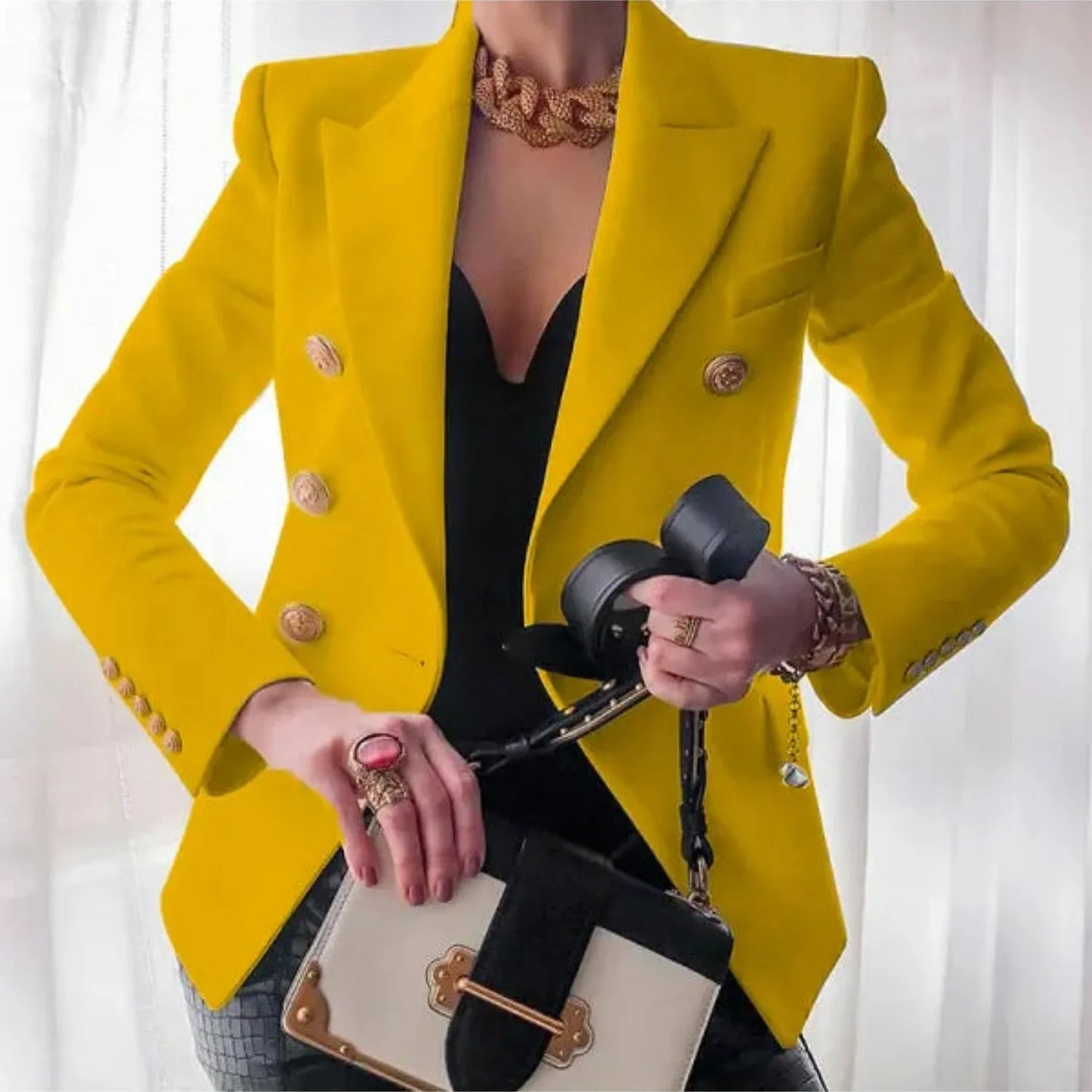Eleganter gelber Blazer mit goldenen Knöpfen, kombiniert mit schwarzem Top und modischer Tasche. Perfekt für stilvolle Damenmode und Business-Looks.