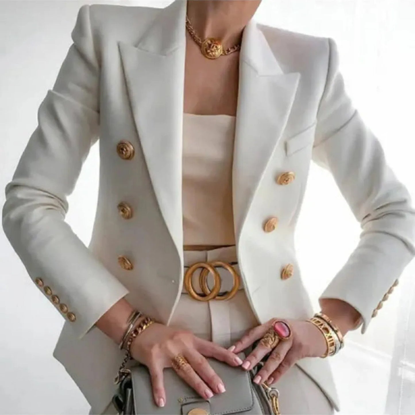 Eleganter weißer Blazer mit goldenen Knöpfen, kombiniert mit passendem Top und Accessoires. Perfekt für stilvolle Business- und Abendmode.