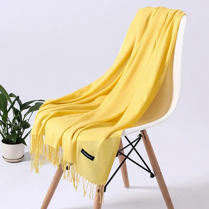 Weicher gelber Schal auf weißem Stuhl, ideal für Herbstmode. Hochwertige Materialien, stilvolles Design, perfektes Accessoire für Damen.