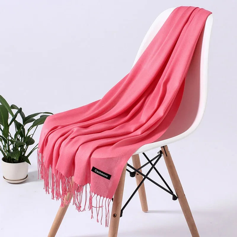 Weicher, rosa Kaschmirschal auf modernem Stuhl, ideal für stilvolle Wintermode. Luxuriöses Accessoire, perfekt für Damenbekleidung.