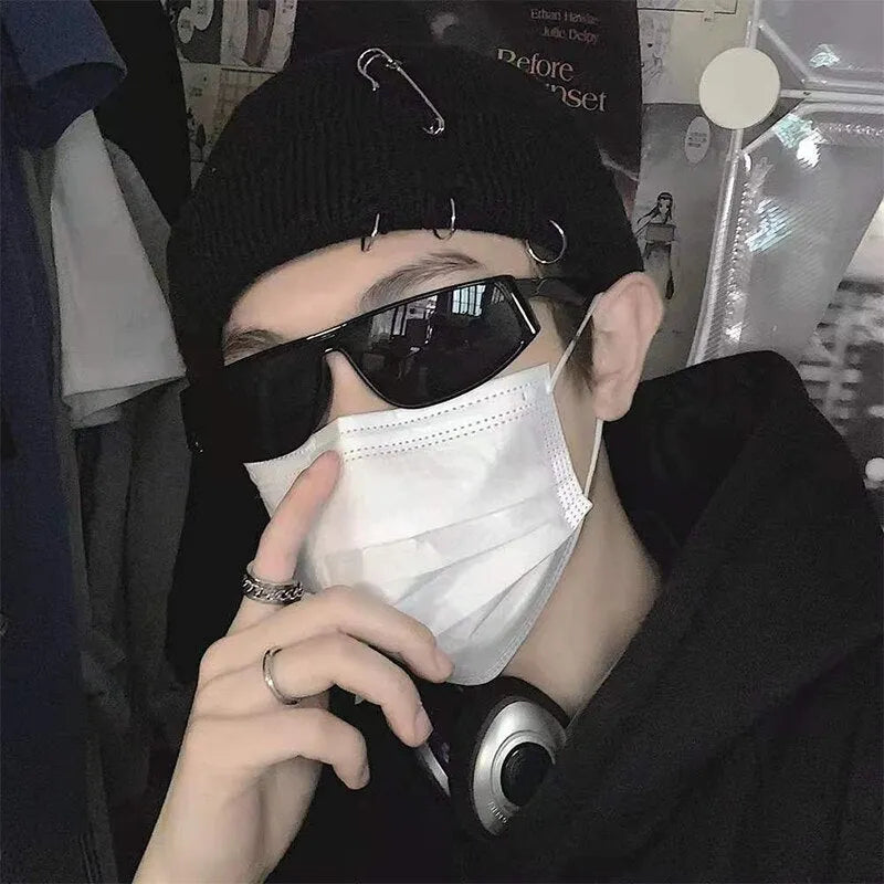 Person mit schwarzer Mütze, Sonnenbrille und Maske, trägt Kopfhörer. Streetwear-Mode, urbaner Stil, trendiges Accessoire, Hip-Hop-Look.