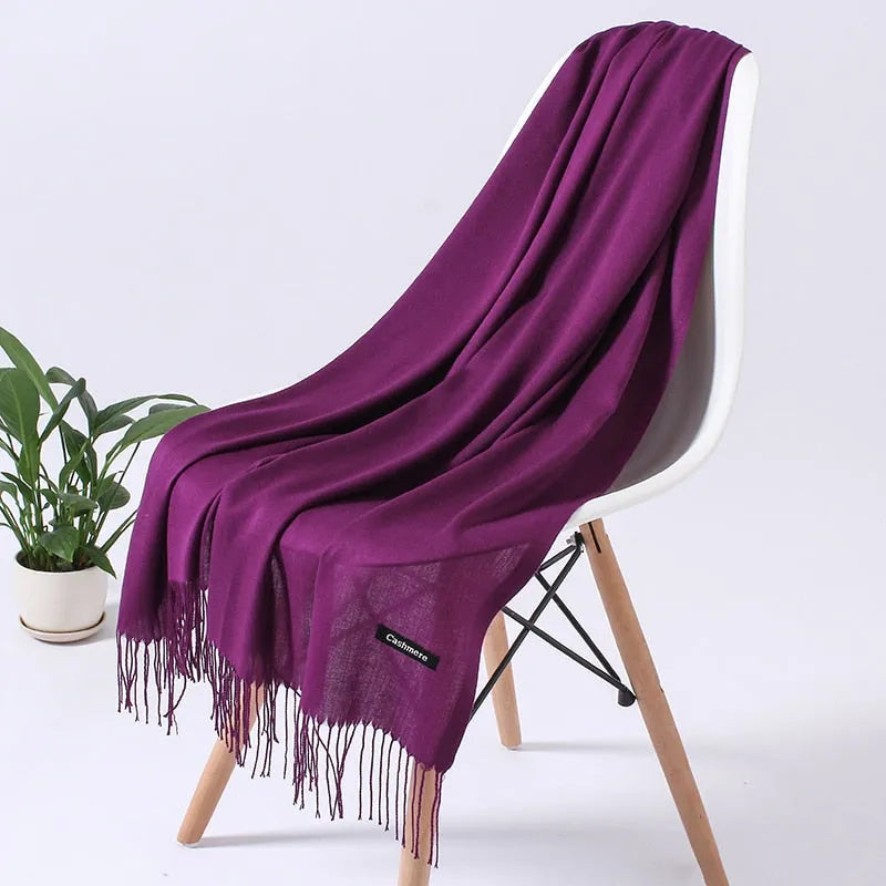 Lila Kaschmirschal auf weißem Stuhl, weiche Textur, elegante Fransen, luxuriöses Accessoire, ideal für Herbst und Wintermode.