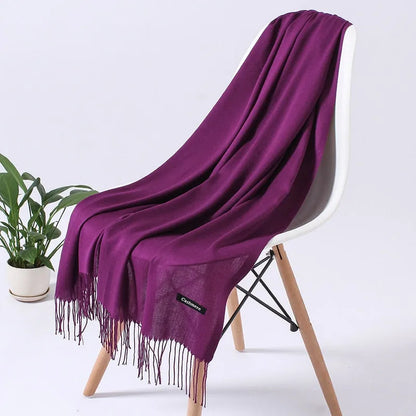 Lila Kaschmirschal auf weißem Stuhl, weiche Textur, elegante Fransen, luxuriöses Accessoire, ideal für Herbst und Wintermode.