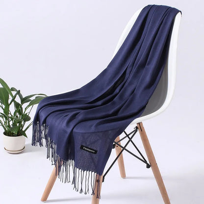 Luxuriöser blauer Kaschmirschal auf modernem Stuhl, ideal für stilvolle Wintermode. Weich, elegant und perfekt als Geschenk.
