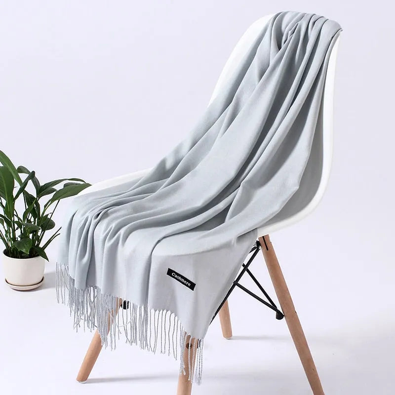 Elegante graue Kaschmirdecke auf modernem Stuhl, ideal für stilvolle Wohnkultur. Weiche, luxuriöse Textur, perfekt für gemütliche Abende.
