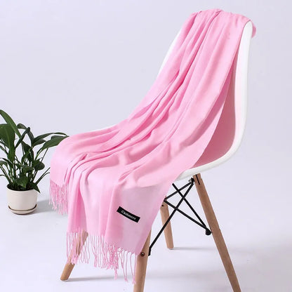 Weicher, rosa Kaschmirschal auf weißem Stuhl, ideal für stilvolle Wintermode. Luxuriöses Accessoire, perfekt für Damenbekleidung.