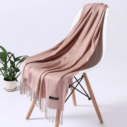 Eleganter rosa Schal aus Kaschmir auf weißem Stuhl, ideal für Herbstmode. Weicher Stoff, Fransen, luxuriöses Accessoire, stilvoller Look.