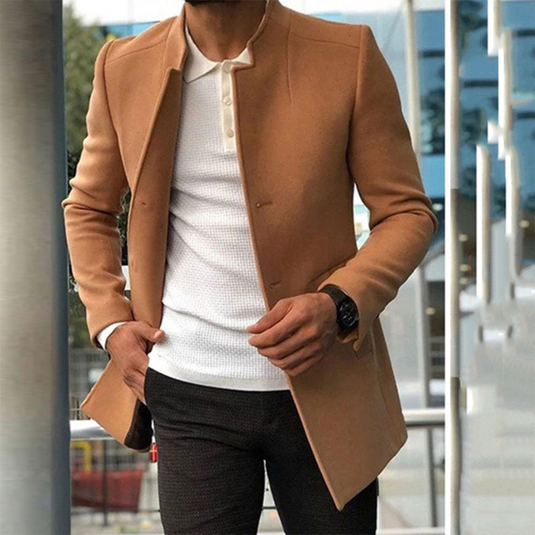 Eleganter Herrenmantel in Kamelhaarfarbe, kombiniert mit weißem Pullover und schwarzer Uhr. Perfekt für stilvolle Herbst- und Wintermode.