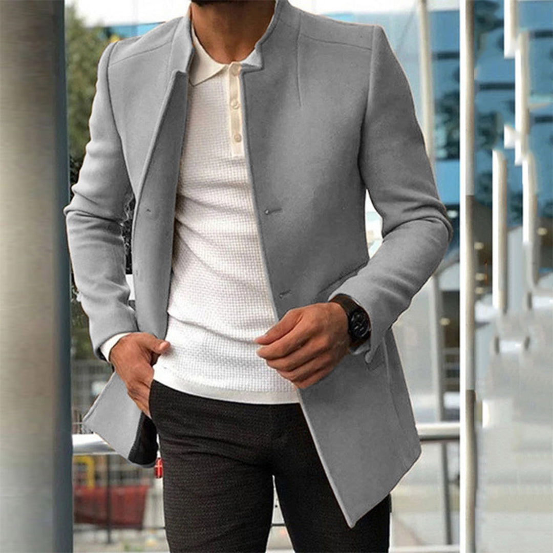 Eleganter Herrenmantel in Grau, kombiniert mit weißem Strickpullover. Perfekt für stilvolle Herbst- und Wintermode. Hochwertige Herrenbekleidung.