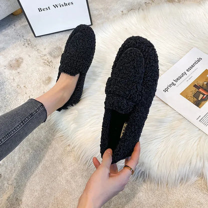 Schwarze, flauschige Hausschuhe auf Teppich, gemütlich und stilvoll. Perfekt für den Winter. Damenmode, Komfort, warme Schuhe, Innenbereich.