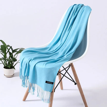 Weicher blauer Schal auf weißem Stuhl, modernes Design, ideal für stilvolle Wohnkultur. Perfekt als Geschenk oder für gemütliche Abende.