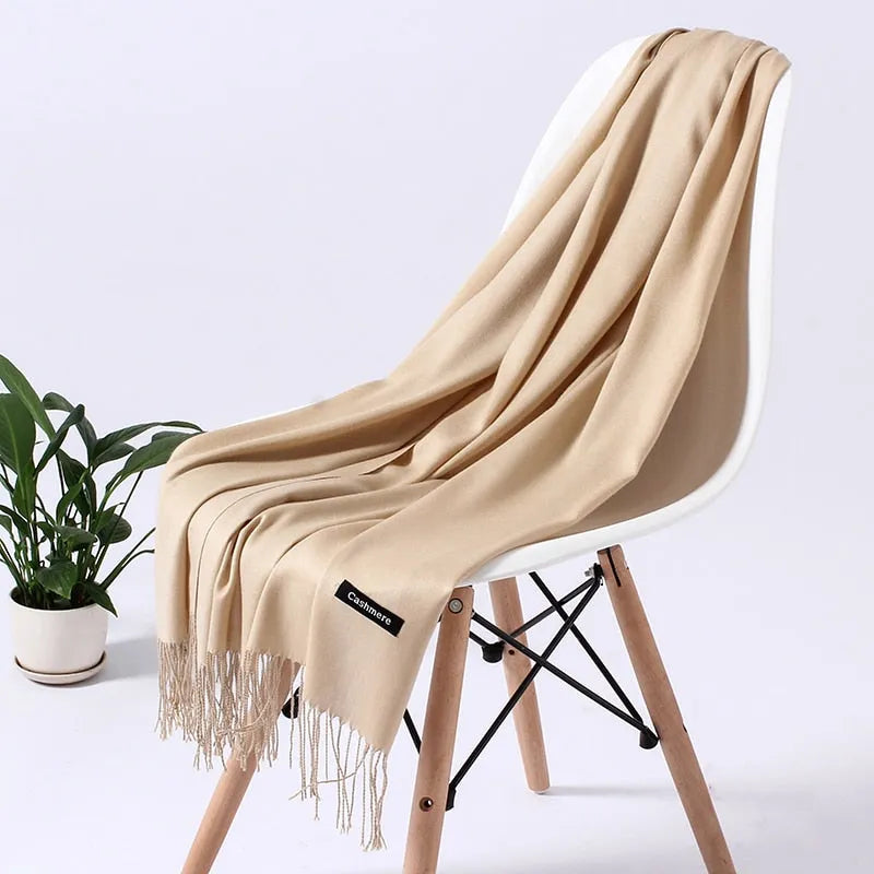 Beige Kaschmirschal auf modernem Stuhl, weiche Textur, ideal für stilvolle Herbst- und Wintermode. Luxuriöses Accessoire, zeitloses Design.