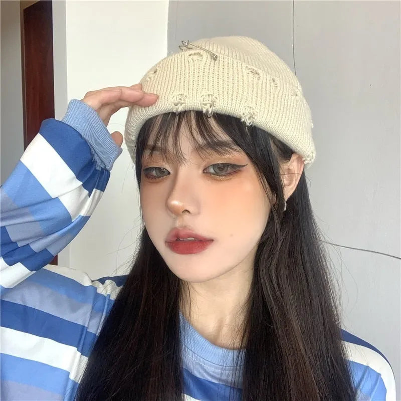 Frau mit beigem Strickmütze und blau-weiß gestreiftem Pullover, modisches Make-up, trendiger Streetwear-Look, asiatische Mode.