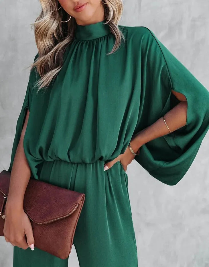Elegantes grünes Kleid mit Fledermausärmeln, kombiniert mit einer braunen Clutch. Perfekt für stilvolle Anlässe und modische Outfits.