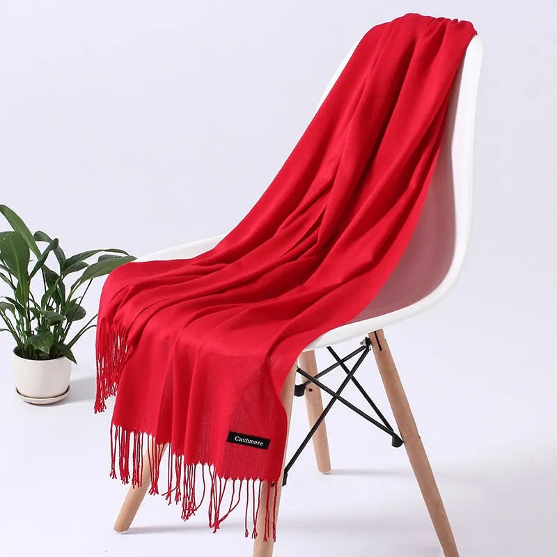 Roter Kaschmirschal auf weißem Stuhl, luxuriös und weich, ideal für stilvolle Wintermode. Perfektes Accessoire für Damen und Herren.