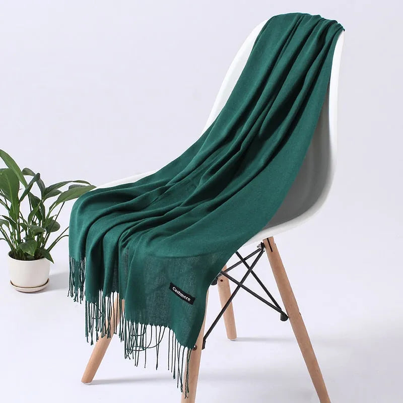 Grüner Kaschmirschal auf weißem Stuhl, elegantes Design, weiches Material, ideal für Herbst und Winter, modisches Accessoire, gemütlich.