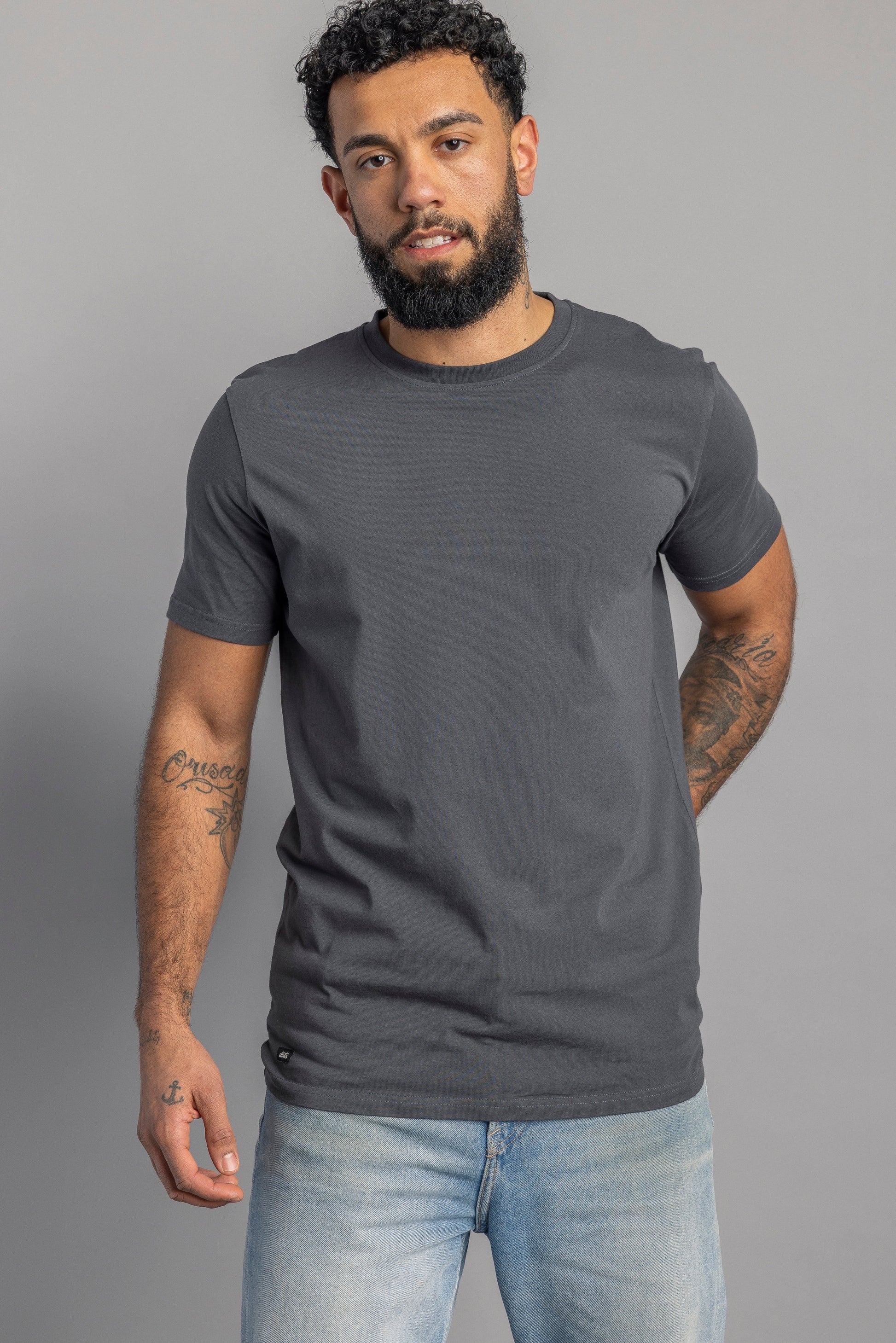 Mann in grauem T-Shirt und blauer Jeans, lässige Mode, Herrenbekleidung, Studioaufnahme.