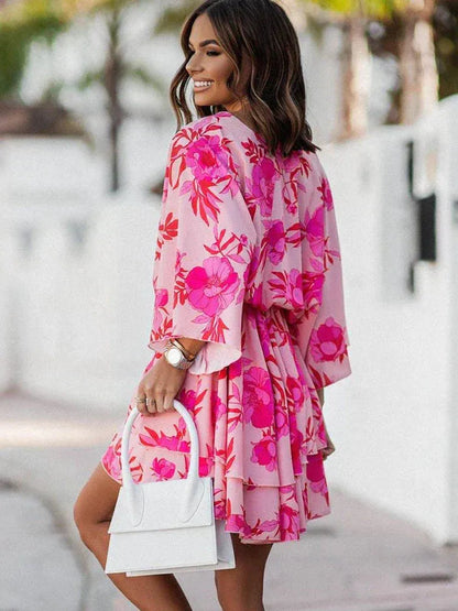 Feminines, kurzes Kleid mit floralem Print in Rosa, V-Ausschnitt und langen Ärmeln. Perfekt für Sommermode und elegante Anlässe.