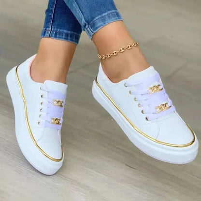 Weiße Sneaker mit goldenen Akzenten und Kettenverzierung, kombiniert mit blauen Jeans. Modische Damen-Schuhe, ideal für Freizeit und Alltag.