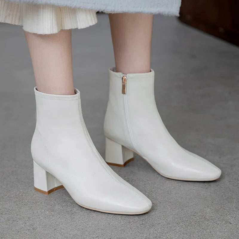 Elegante weiße Damenstiefeletten mit Blockabsatz und Reißverschluss, ideal für Herbstmode. Perfekt kombinierbar zu Röcken und Hosen.