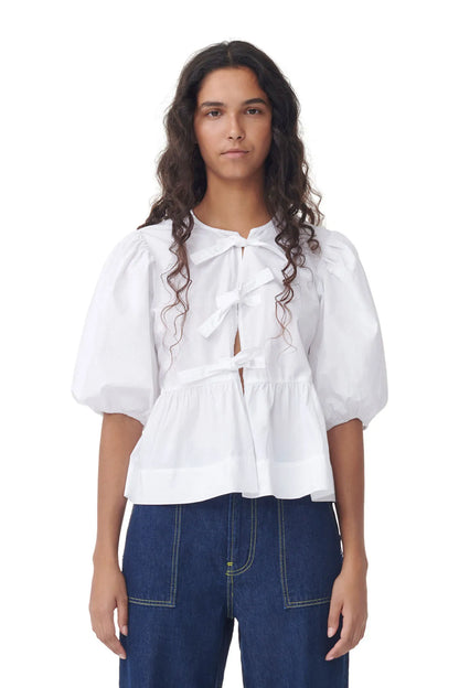 Weiße Bluse mit Puffärmeln und Schleifen, kombiniert mit dunkelblauer Jeans. Modetrend, Damenmode, eleganter Look, stilvolle Kleidung.