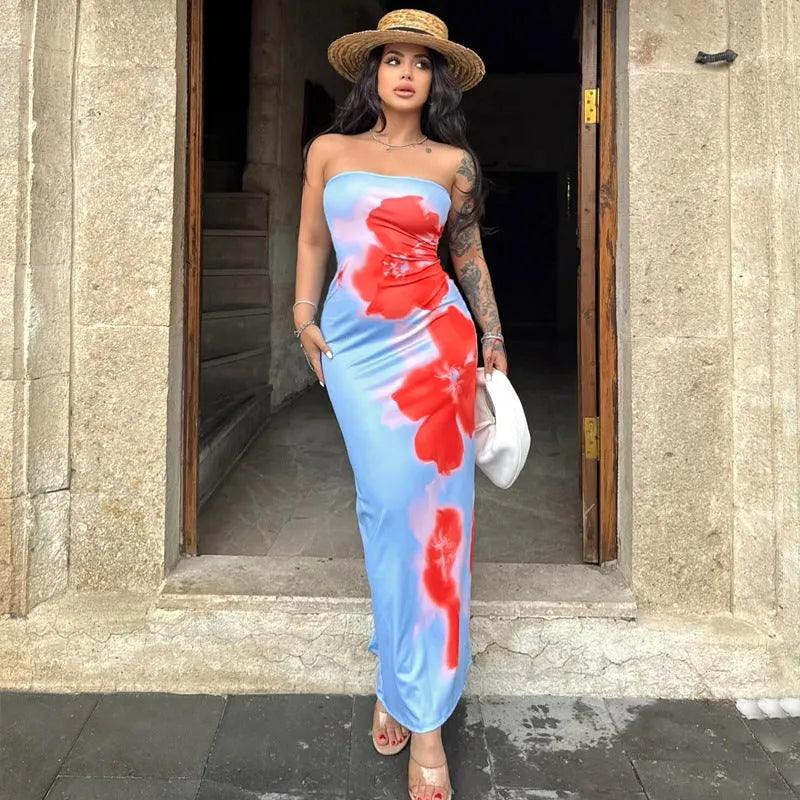 Frau in blauem, schulterfreiem Kleid mit roten Blumen, Strohhut und Tätowierungen. Sommermode, elegantes Kleid, florales Design.