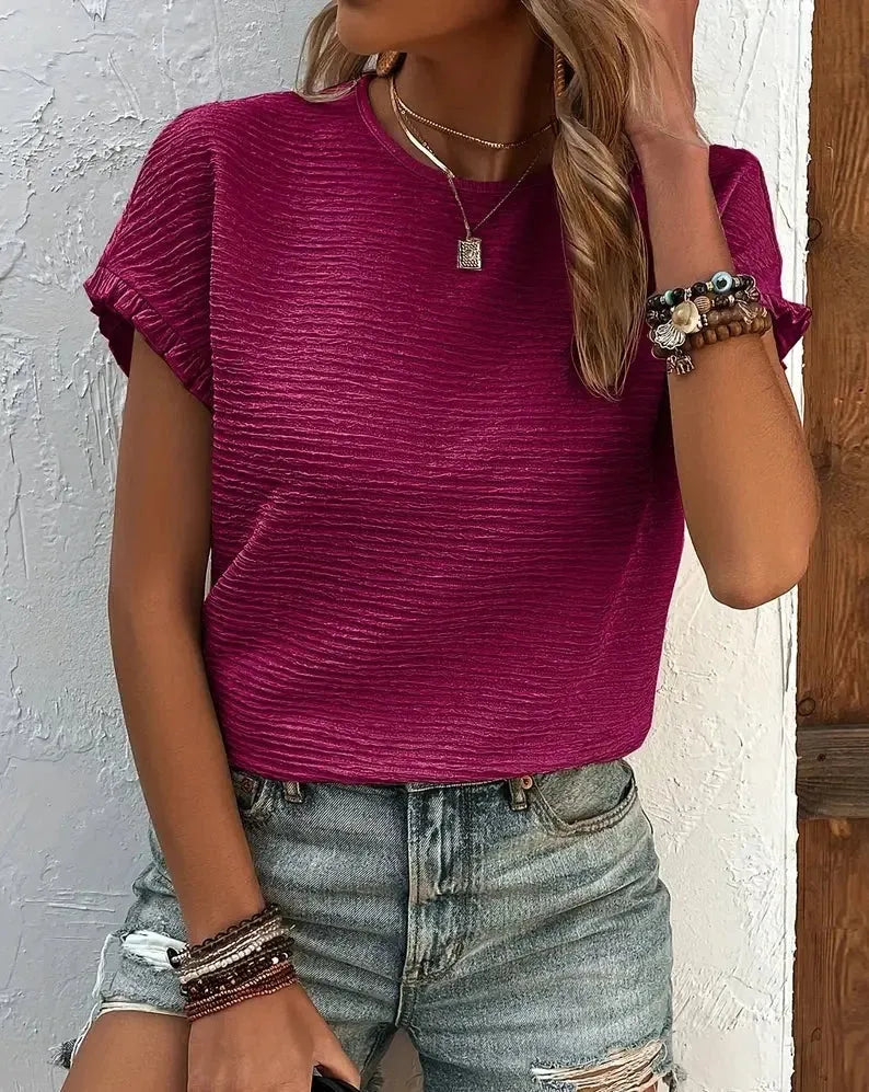 Damenmode: Lässiges, geripptes, pinkes T-Shirt kombiniert mit modischen, zerrissenen Jeansshorts. Perfekt für Sommer und Freizeit.
