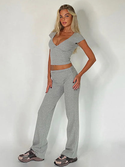 Graues Damen-Trainingsset mit V-Ausschnitt und ausgestellten Hosen. Perfekt für Fitness, Yoga und Freizeit. Bequem und stilvoll.