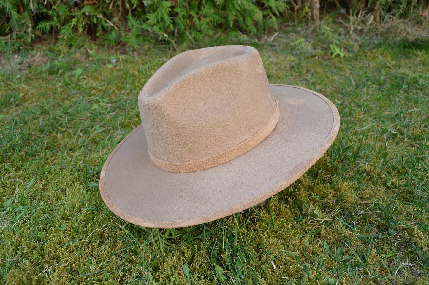 Breiter Filzhut in Beige auf grünem Gras, ideal für Outdoor-Abenteuer. Perfekt für stilvolle Herrenmode und Sonnenschutz.