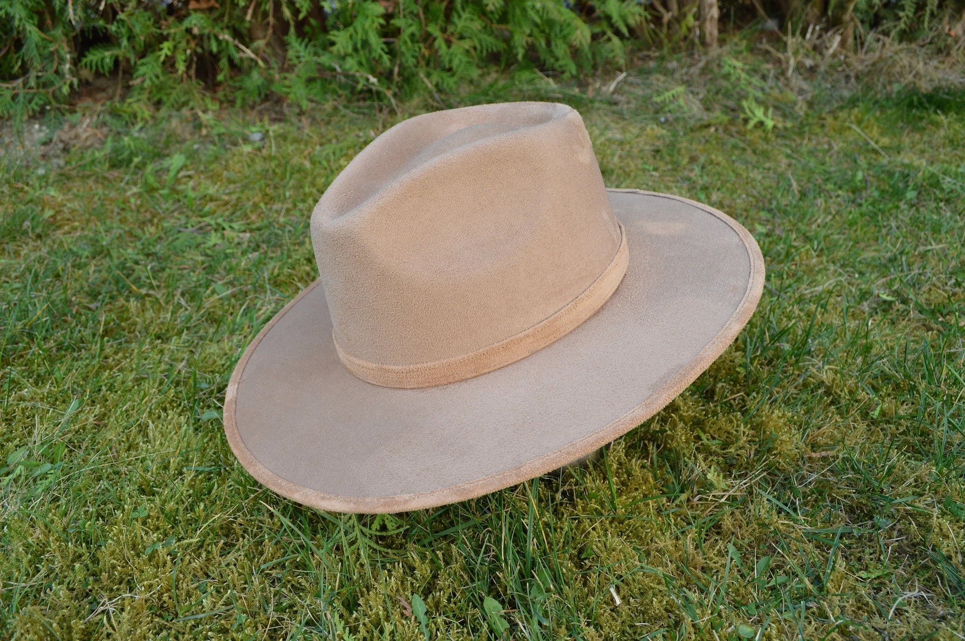 Breiter Filzhut in Beige auf grünem Gras, ideal für Outdoor-Abenteuer. Perfekt für stilvolle Herrenmode und Sonnenschutz.