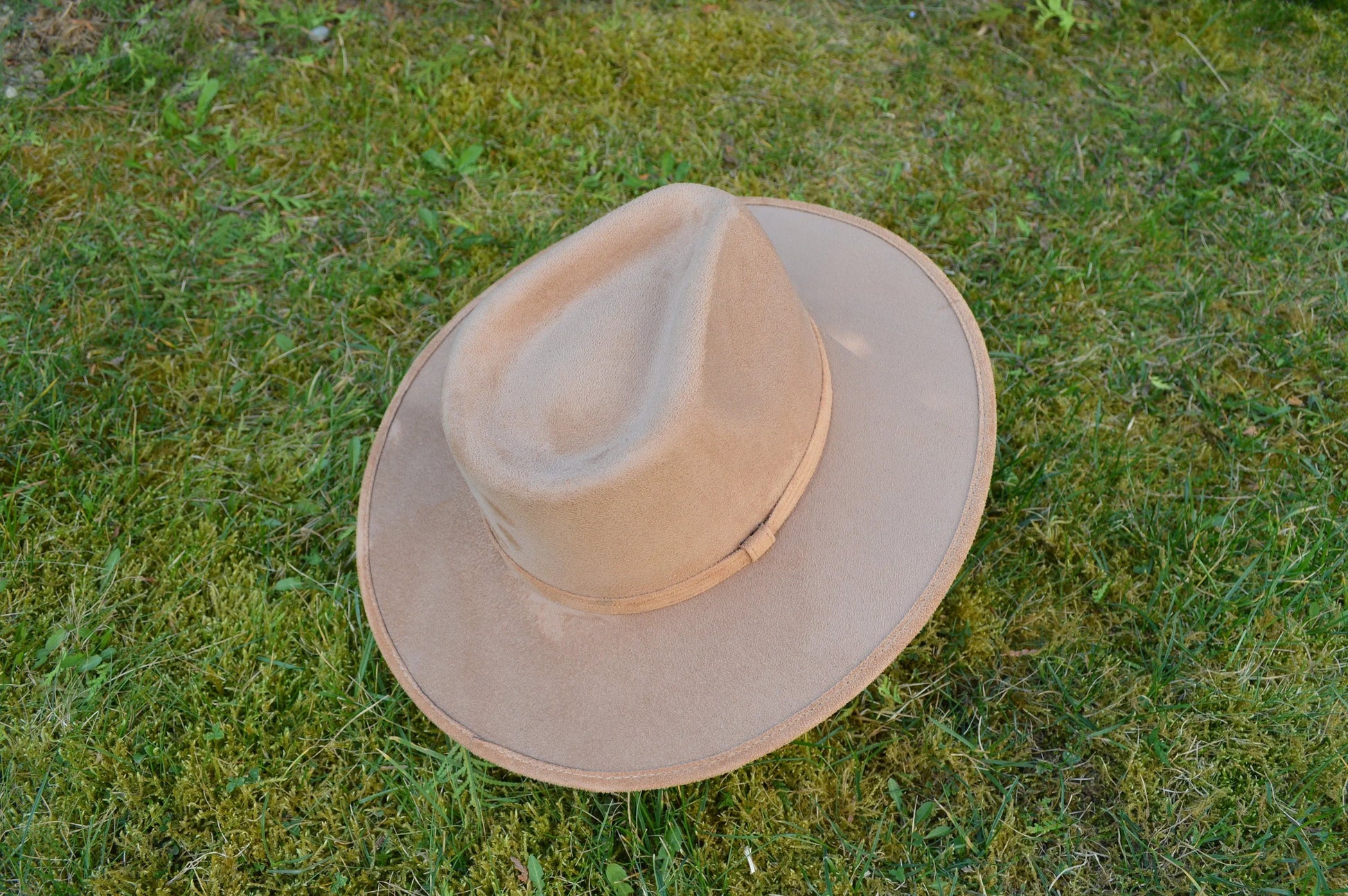 Breiter, beiger Filzhut auf grünem Gras. Perfekt für Outdoor-Abenteuer, stilvoll und funktional. Ideal für Wanderungen und Sonnenschutz.