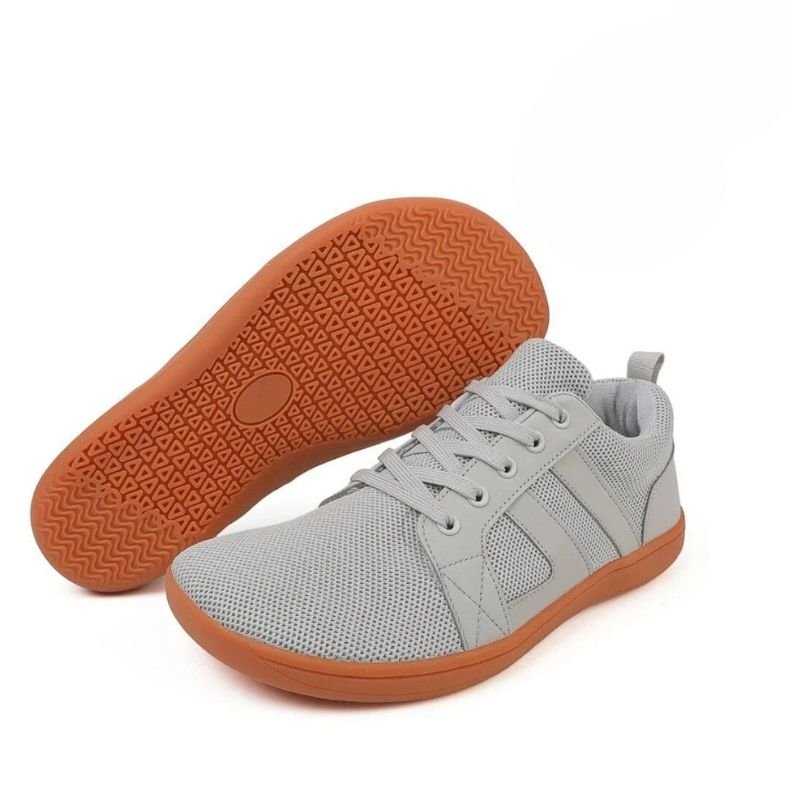 Graue Barfuß-Sneaker mit oranger Sohle, atmungsaktives Mesh, ideal für Freizeit und Sport.