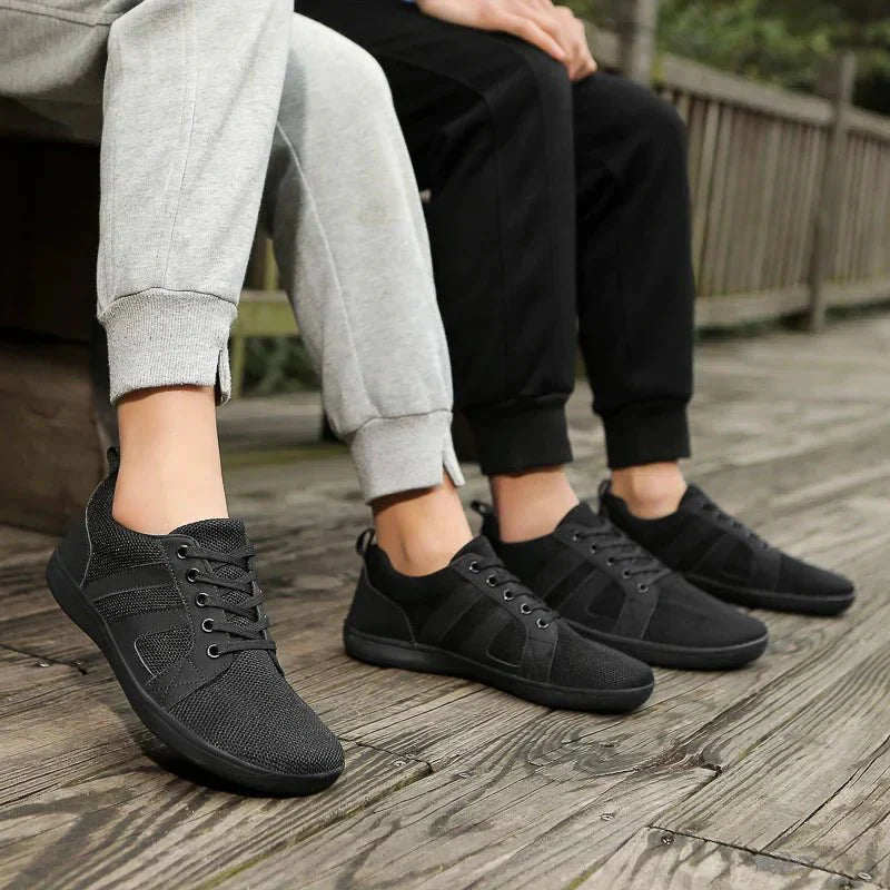 Schwarze Barfuß-Sneakers, atmungsaktiv, unisex, auf Holzterrasse, sportlich, bequem.