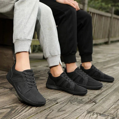 Schwarze Barfuß-Sneakers, atmungsaktiv, unisex, auf Holzterrasse, sportlich, bequem.