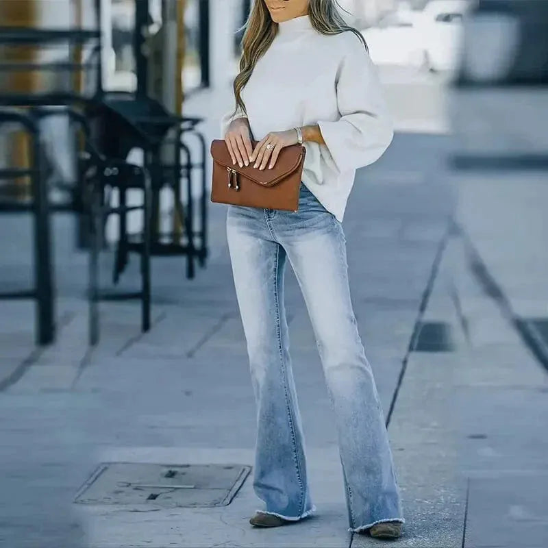 Damen Flared Jeans, hellblau, kombiniert mit weißem Pullover und brauner Tasche. Modetrend, lässiger Streetstyle, Herbstmode.